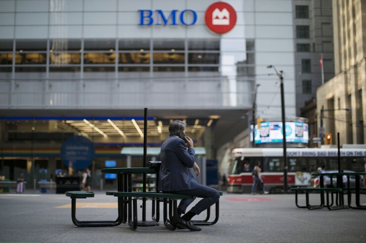 A man holds a smartphone while sitting outside of a Bank of Montreal (BMO) building in the financial district of Toronto, Ontario, Canada, on Wednesday, July 11, 2018. Canadian stocks were mixed Friday as health care tumbled and energy rose, even as was still on pace for a weekly loss amid escalating trade war risks. Photographer: Brent Lewin/Bloomberg