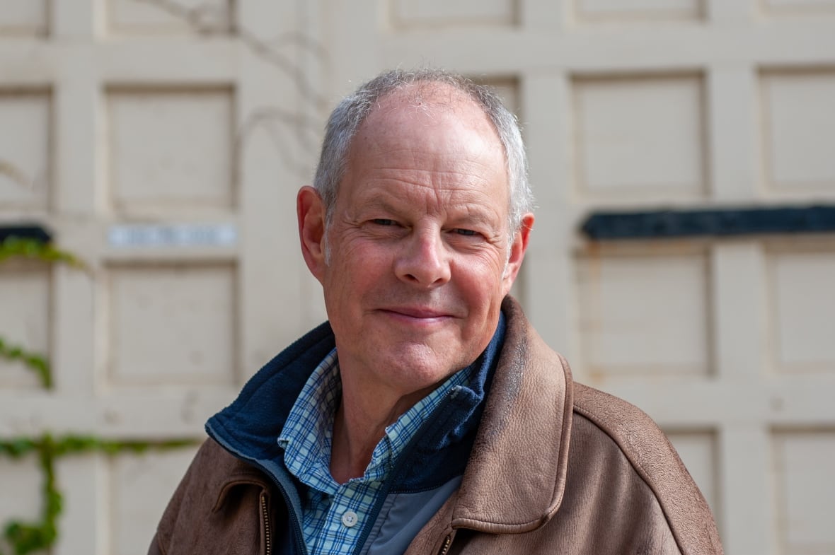 A man with grey hair wearing a leather jacket.