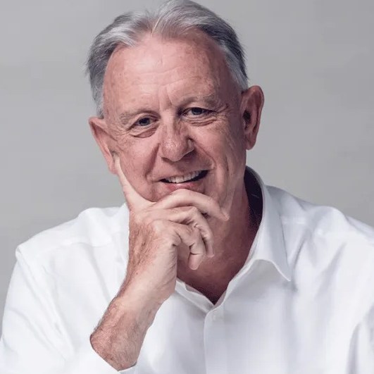 Portrait of Mark Clare, Chair, smiling and resting his chin on his hand.