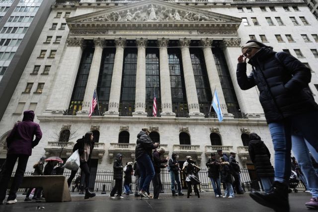 People stand in front of the New York Stock Exchange in New York, Monday, April 7, 2025. (AP Photo/Seth Wenig)
